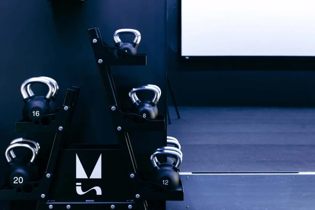 Close-up of kettlebell storage rack with branded logo inside studio training room