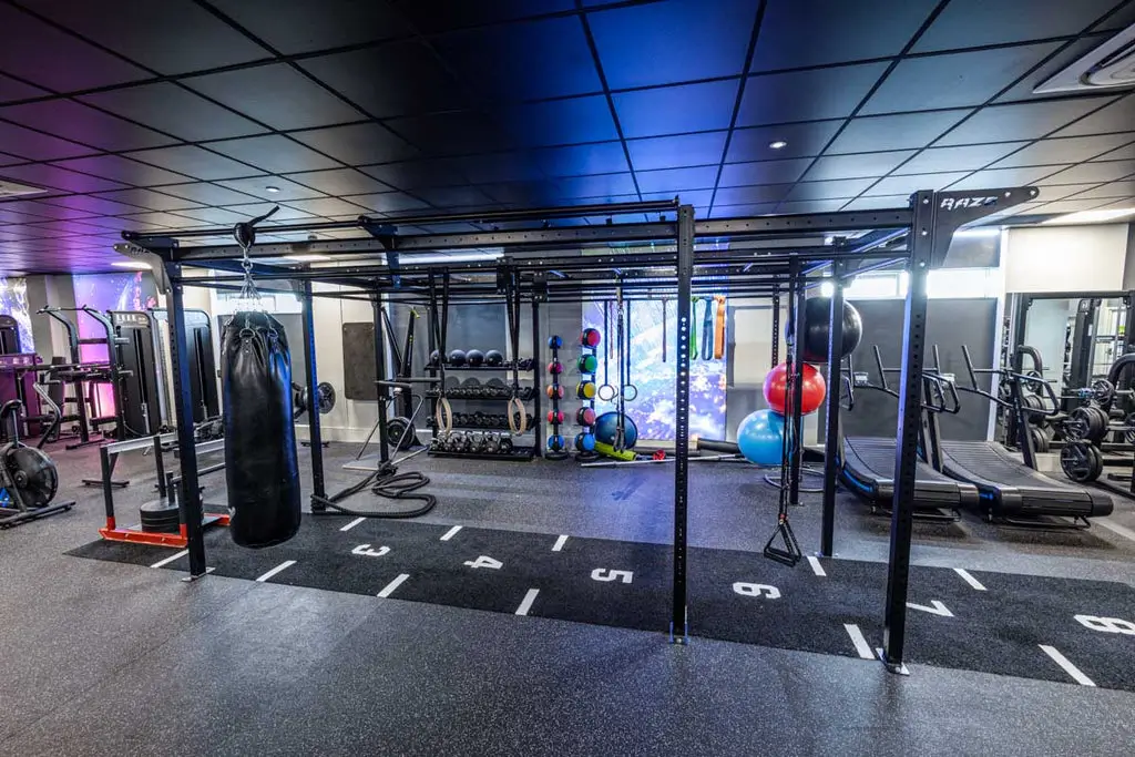 Multi-station functional training rig with punch bag, kettlebells, and stability balls in gym