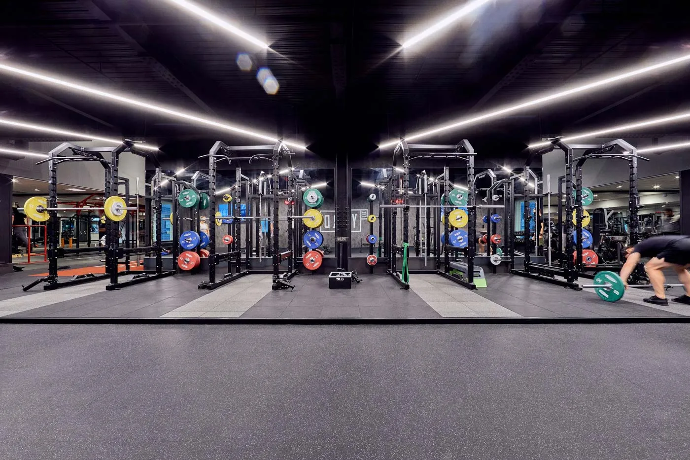 Rows of power racks with colourful weight plates inside The Ministry gym London