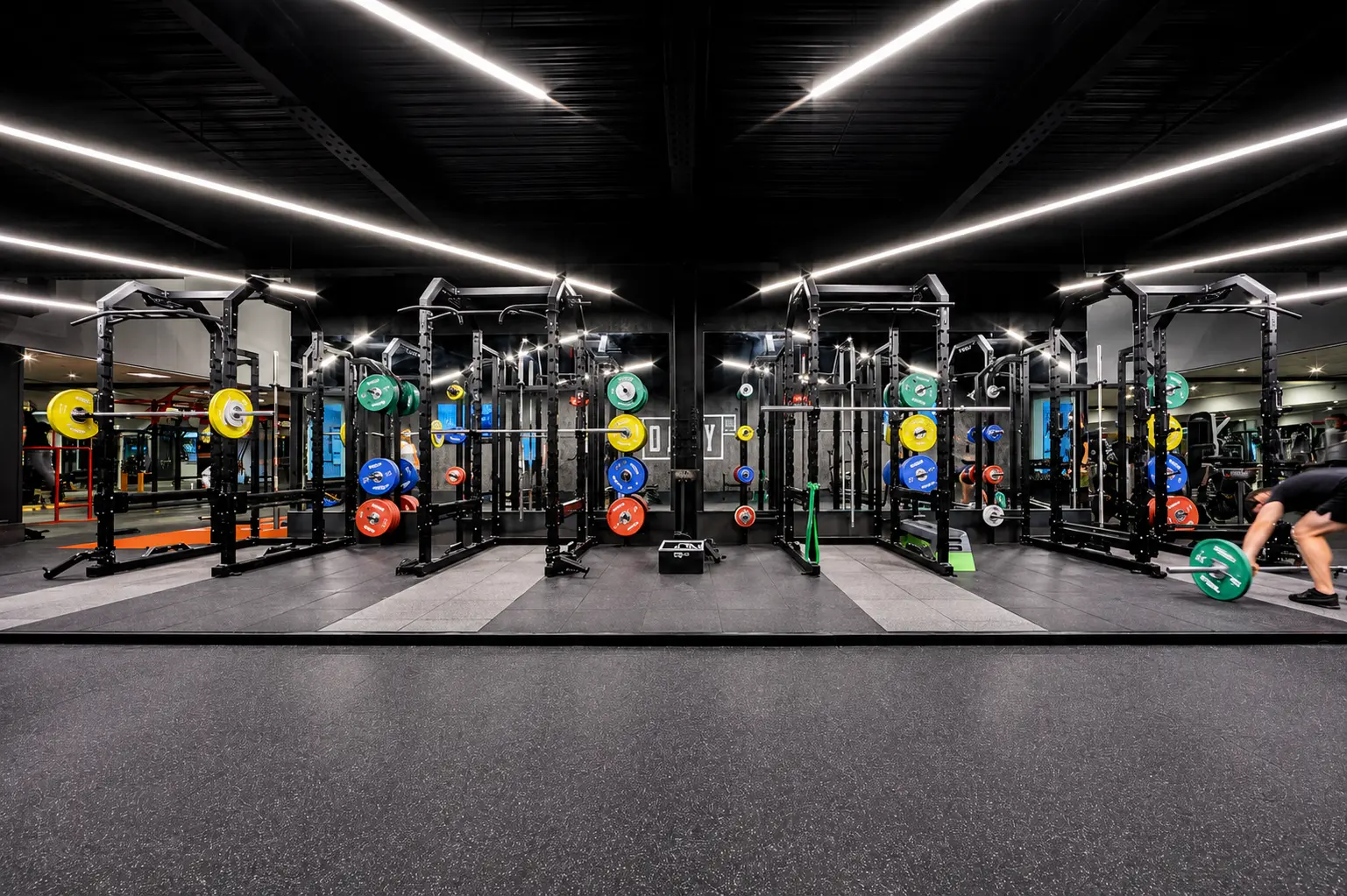 Rows of power racks with colourful weight plates inside The Ministry gym London