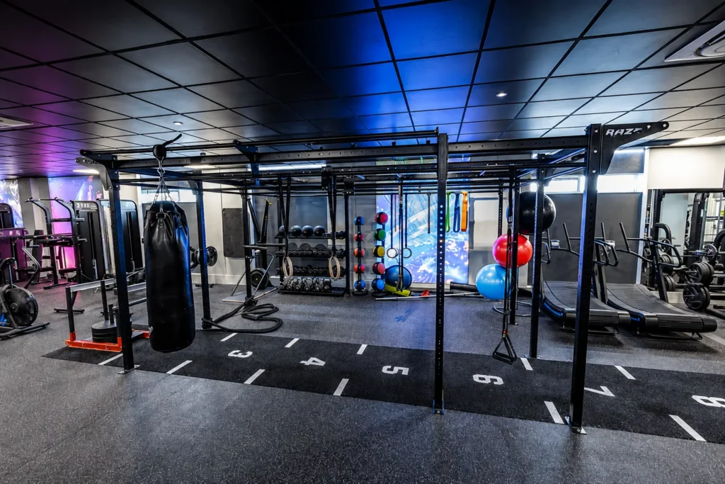 Multi-station functional training rig with punch bag, kettlebells, and stability balls in gym