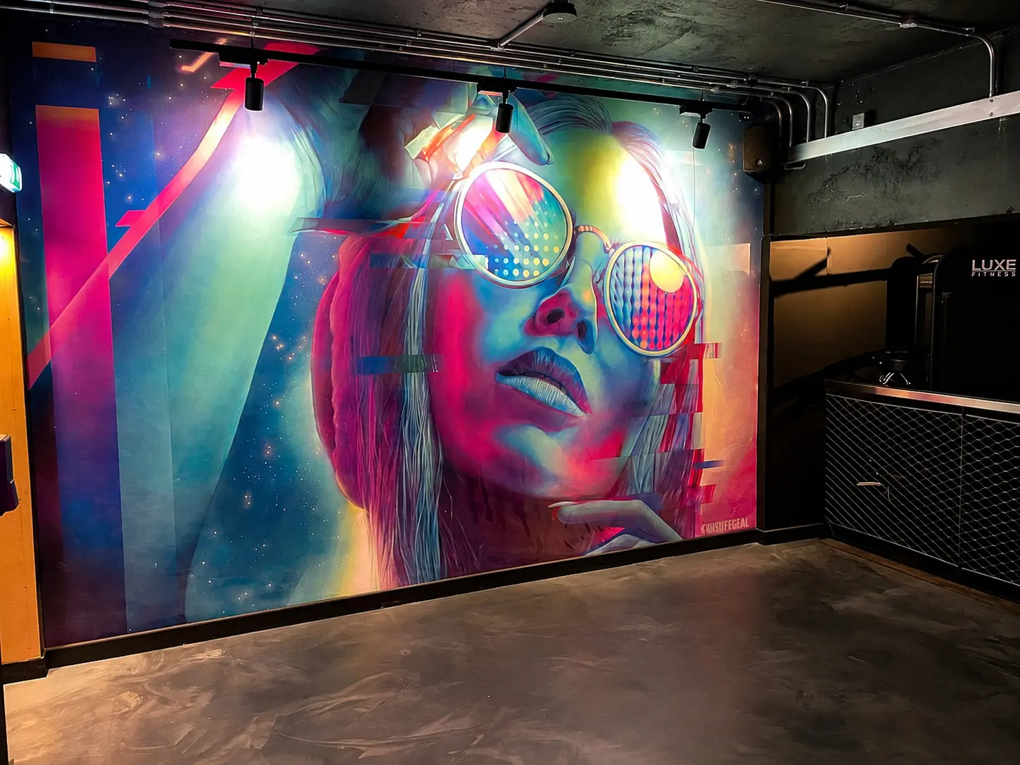 Vivid glitch-style mural artwork of a woman in sunglasses inside Luxe Fitness Bristol gym