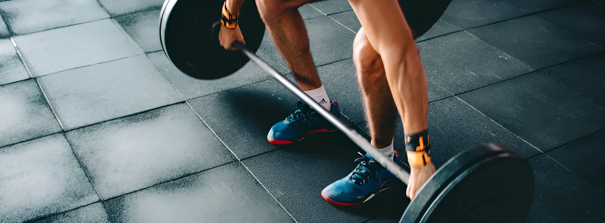 Close-up of athlete's hands gripping barbell during deadlift on gym rubber flooring