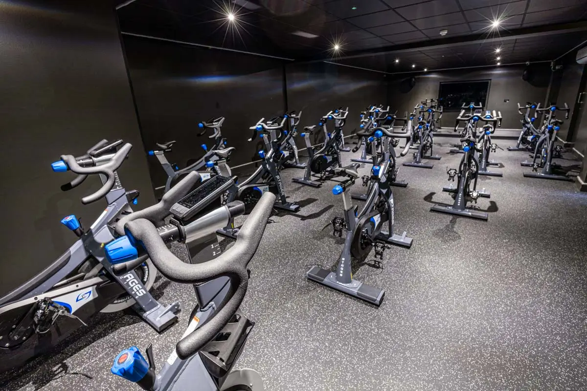 Strength equipment, benches, and squat racks arranged along a mirrored commercial gym wall